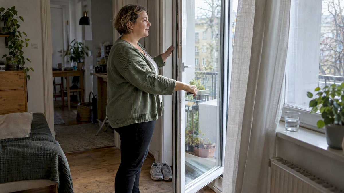 Morgens öffnet die Frau die Tür zum Balkon.